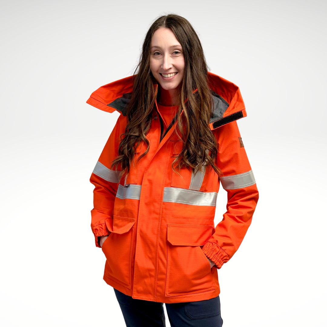 Image of women's FR parka jacket. Women's FR Parka is bright orange in colour with silver reflective tape on torso and arms. Inner lining is MWG BLOCKER fleece, bright orange in colour. 4 large front pockets and hood flaps are seen in image. Women's FR Parka is made with an inherent flame-resistant (FR) fabric. Zips in to women's FR freezer jacket and women's FR hoodie.