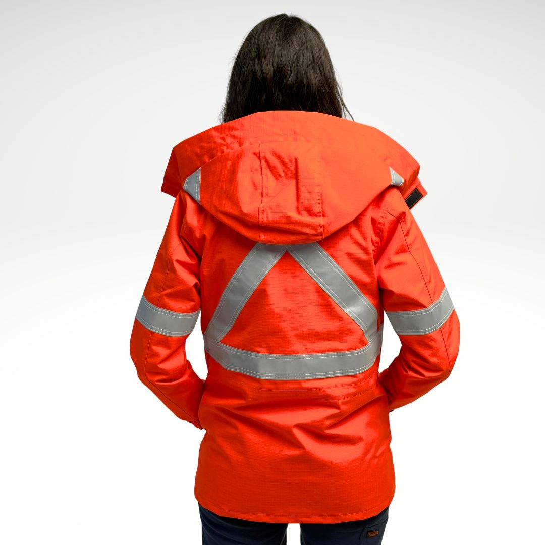 Image of women's FR parka jacket. Women's FR Parka is bright orange in colour with silver reflective tape on torso and arms. Inner lining is MWG BLOCKER fleece, bright orange in colour. 4 large front pockets and hood flaps are seen in image. Women's FR Parka is made with an inherent flame-resistant (FR) fabric. Zips in to women's FR freezer jacket and women's FR hoodie.