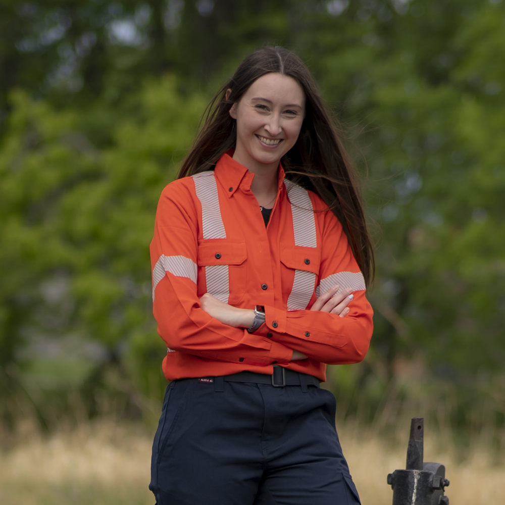 MWG COMFORT WEAVE Women's FR Shirt. Women's FR Shirt is bright orange with silver segmented reflective striping on torso, sleeves, and back for high-visibility. Women's FR Shirt has black FR buttons, two large chest pockets with flaps, and a dress shirt collar. Women's FR Shirt is made with MWG COMFORT WEAVE, an inherently flame-resistant fabric. Women's FR Shirt is lightweight and breathable, perfect for work in warm weather.