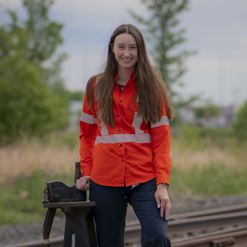 Image of MWG COMFORT WEAVE Women's FR Button Shirt. Women's FR Shirt is bright orange in colour with silver segmented reflective tape on torso and sleeves to meet high-visibility standard CSA Z96-15. Women's FR Shirt has a dress-shirt style collar and two large chest pockets with buttons. MWG COMFORT WEAVE is a lightweight inherent FR fabric. 