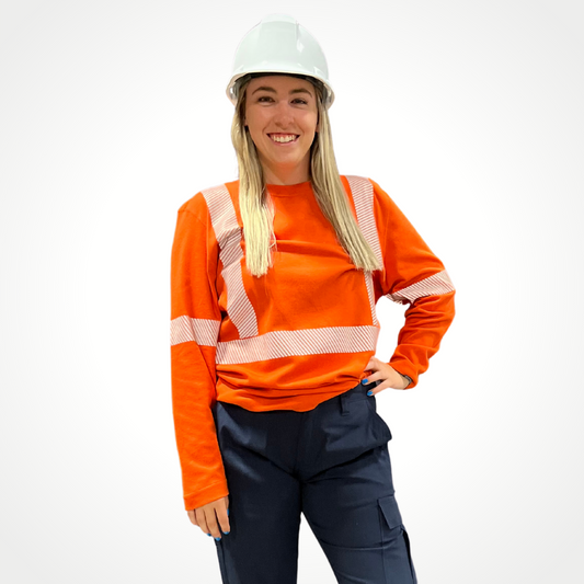 MWG EVOLUTION Women's FR Shirt. Women's FR Shirt is bright orange with silver segmented reflective striping on torso and sleeves for high-visibility. FR Shirt is made with MWG EVOLUTION, an inherently flame-resistant lightweight fabric. Model is wearing women's FR Shirt with women's FR Pants.