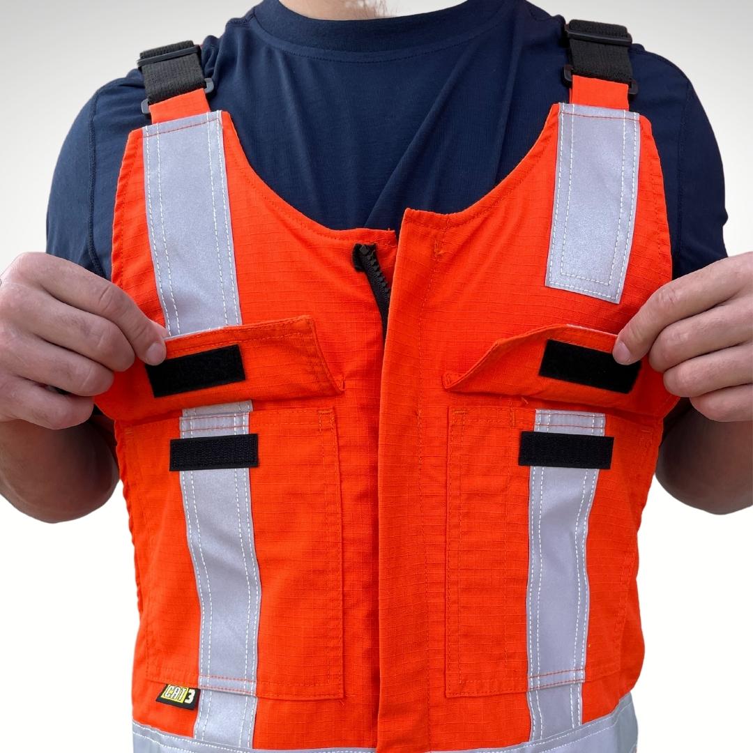 MWG RIPGUARD Men's FR Overalls. FR Overalls are made with MWG RIPGUARD, an inherently flame-resistant ripstop fabric. FR Overalls are bright orange and navy with silver reflective striping for high-visibility. Image displays velcro closures on chest pockets. FR Overalls have black FR adjustable straps.