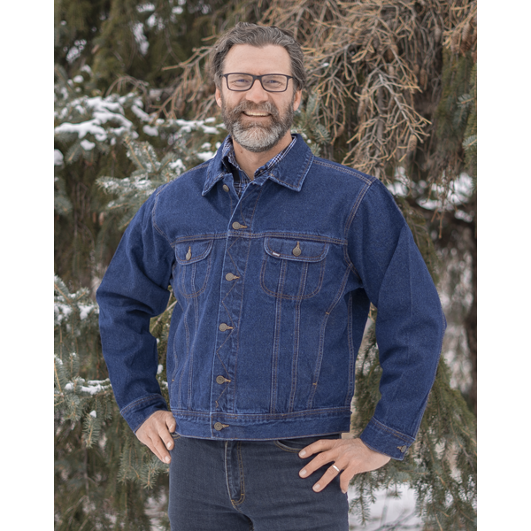 Image of MWG Storm Rider Men's Denim Jacket. MWG jean jacket is navy in colour with gold stitching and buttons. Denim jacket has two large chest pockets and slant pockets on lower torso. Model is wearing MWG Storm Rider Jacket with MWG stretch denim blue jeans.