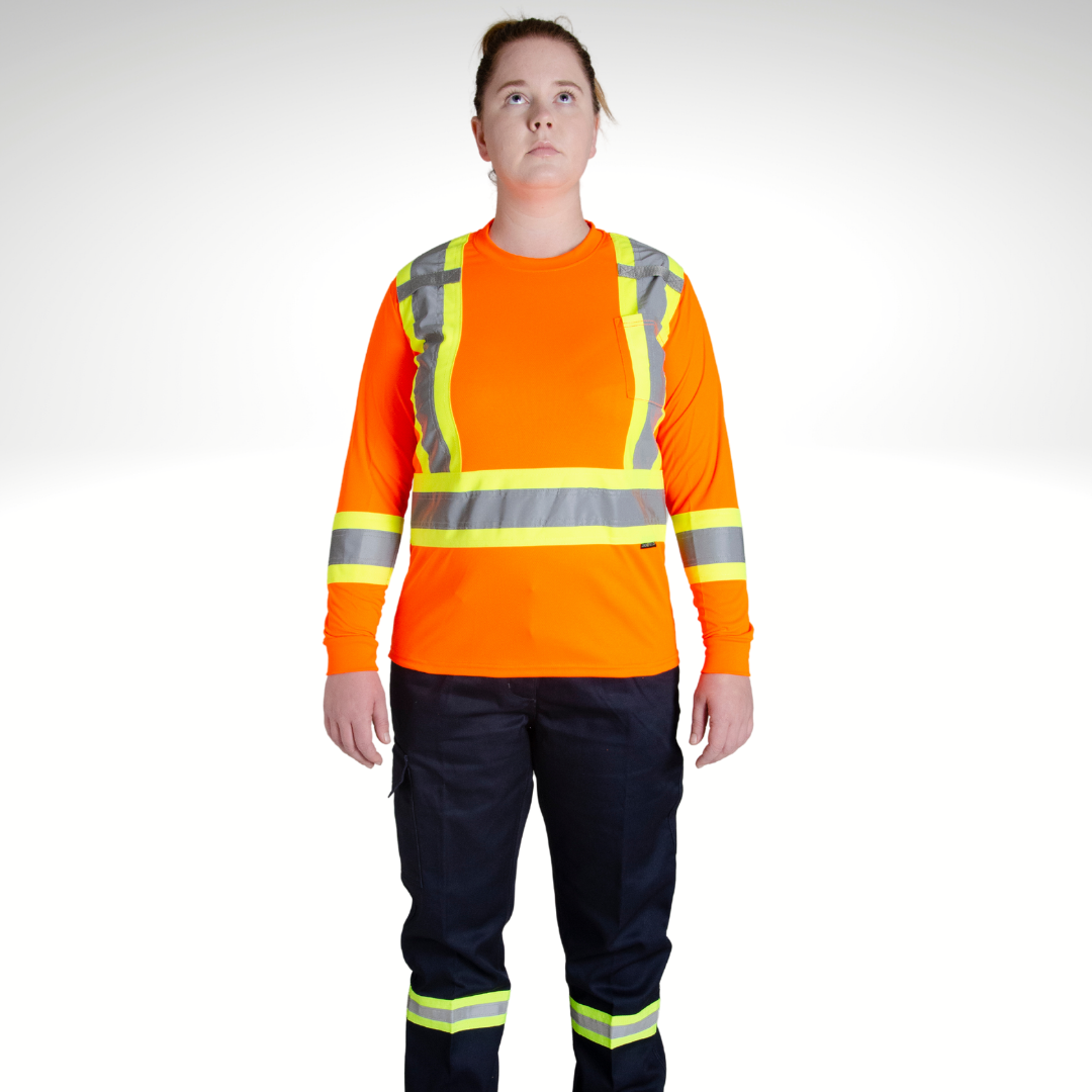 Image of MWG Women's Hi-Vis Long Sleeve T-Shirt. Women's Long Sleeve shirt is bright orange with yellow/silver/yellow reflective tape on torso and sleeves to meet high-visibility standard CSA Z96-15. Model is wearing Hi-Vis Shirt with navy Hi-Vis cargo pants.