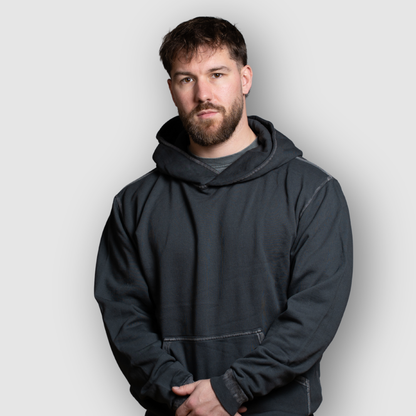 Man wearing a dark gray hoodie against a light gray background
