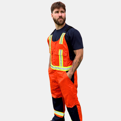 Image of MWG COTTON COMFORT FR Bib Overall. The FRC bib overall is bright orange and navy in colour, with yellow/silver/yellow reflective tape on torso and legs. Image shows two large front pockets on chest and two front slant pockets on hips. Overall is made with MWG COTTON COMFORT flame-resistant (FR) cotton.