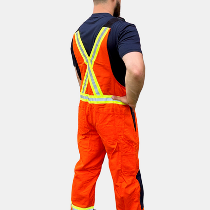 Image of MWG COTTON COMFORT FR Bib Overall. The FRC bib overall is bright orange and navy in colour, with yellow/silver/yellow reflective tape on torso and legs. Image shows two large front pockets on chest and two front slant pockets on hips. Overall is made with MWG COTTON COMFORT flame-resistant (FR) cotton.