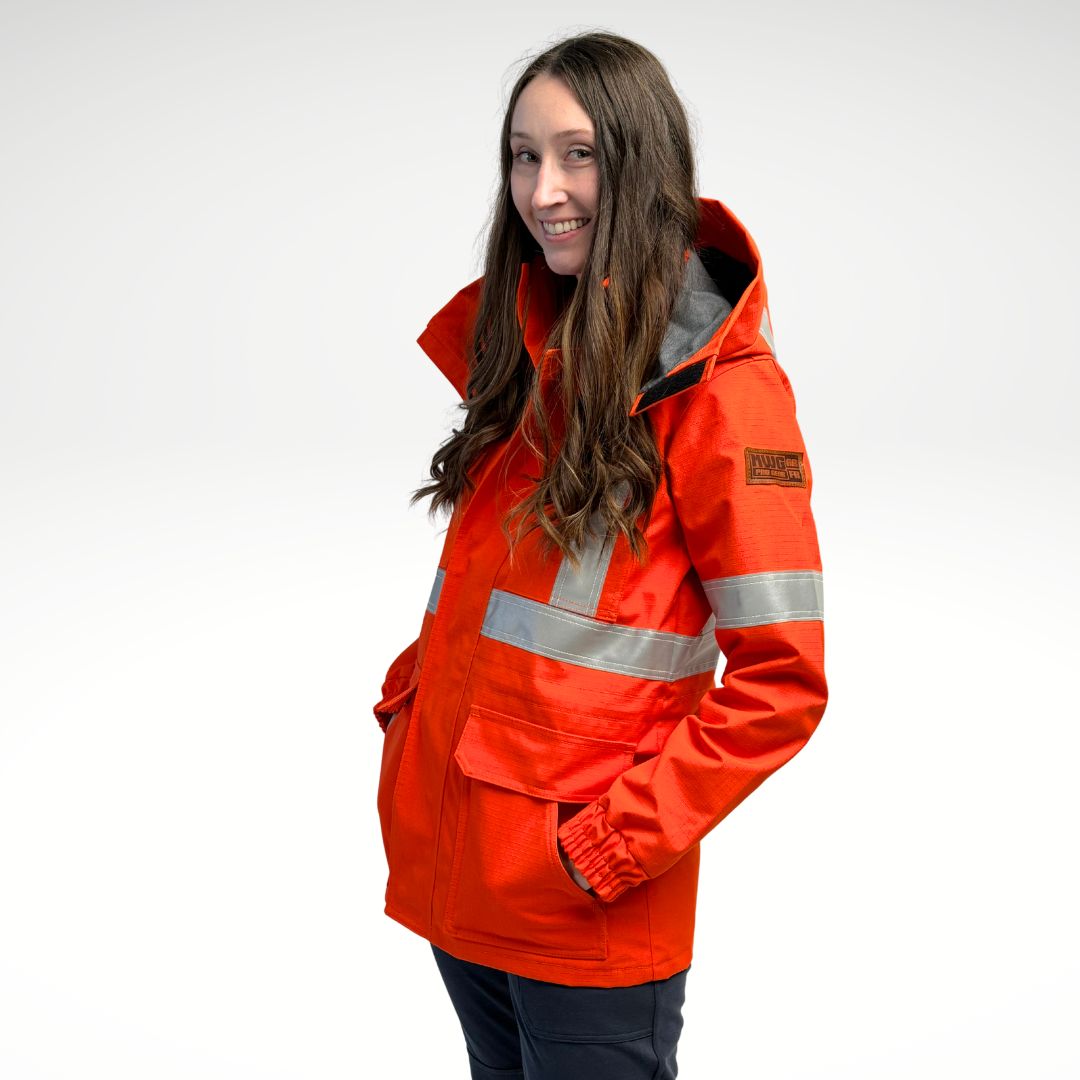 Image of women's FR parka jacket. Women's FR Parka is bright orange in colour with silver reflective tape on torso and arms. Inner lining is MWG BLOCKER fleece, bright orange in colour. 4 large front pockets and hood flaps are seen in image. Women's FR Parka is made with an inherent flame-resistant (FR) fabric. Zips in to women's FR freezer jacket and women's FR hoodie.
