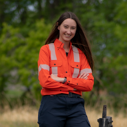 MWG COMFORT WEAVE Women's FR Shirt. Women's FR Shirt is bright orange with silver segmented reflective striping on torso, sleeves, and back for high-visibility. Women's FR Shirt has black FR buttons, two large chest pockets with flaps, and a dress shirt collar. Women's FR Shirt is made with MWG COMFORT WEAVE, an inherently flame-resistant fabric. Women's FR Shirt is lightweight and breathable, perfect for work in warm weather.