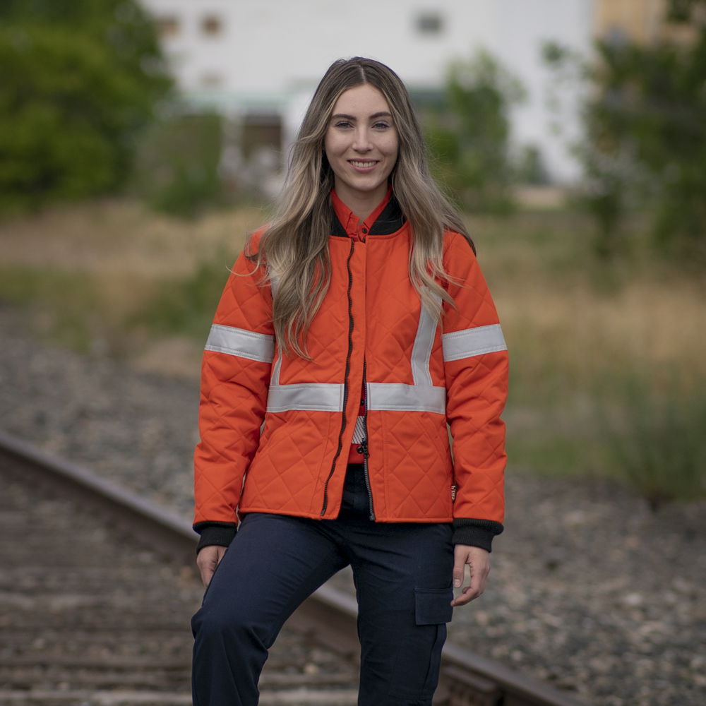 Image of MWG Women's FR freezer jacket. Women's FR Freezer Jacket is bright orange in colour with silver reflective tape on arms and torso to meet high-visibility standard CSA Z96-15. Collar and cuffs are black as well as front zipper. Women's FR Freezer Jacket is made with an inherent flame-resistant (FR) fabric.