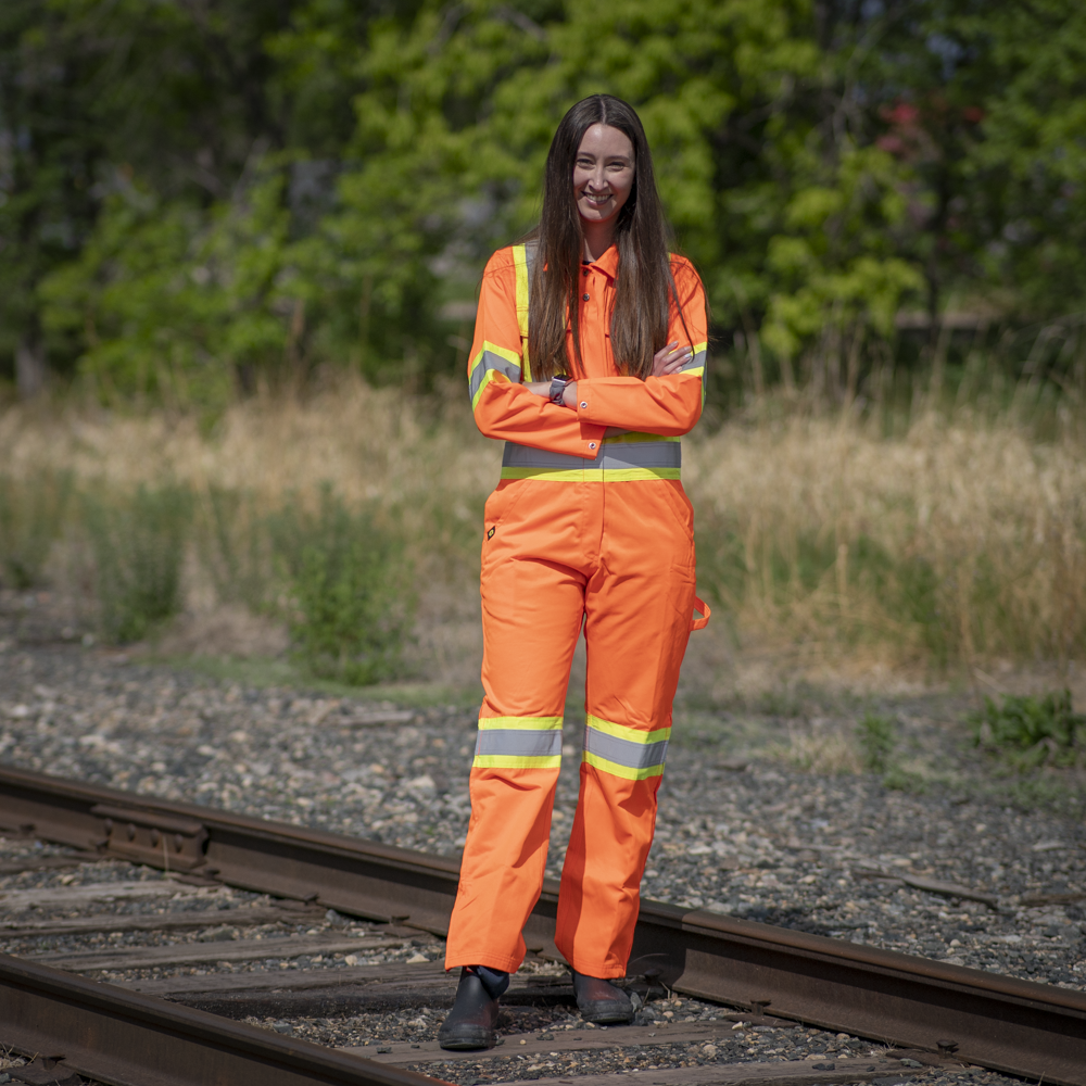 Image of MWG Women's Hi-Vis Coverall. Women's Coverall is bright orange in colour with yellow/silver/yellow reflective tape on torso, sleeves, and legs to meet high-visibility standard CSA Z96-15. Hi-Vis Coverall is a women's fit.