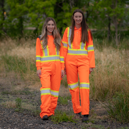 Image of MWG Women's Hi-vis Bib Overall. Women's Overall is bright orange in colour with yellow/silver/yellow reflective tape on torso and legs to meet high-visibility standard CSA Z96-15. MWG Hi-Vis Overall is a women's fit.