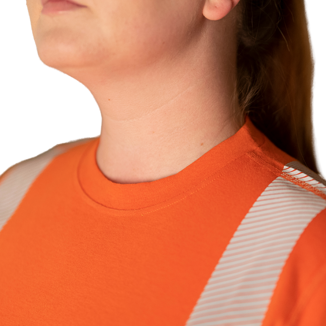 Close up image of MWG EVOLUTION Women's FR Shirt. Women's FR Shirt is bright orange in colour with silver segmented reflective tape on torso. Silver segmented reflective tape is heat-sealed for lightweight feel and less bulk. MWG EVOLUTION is a lightweight inherent flame-resistant (FR) fabric.