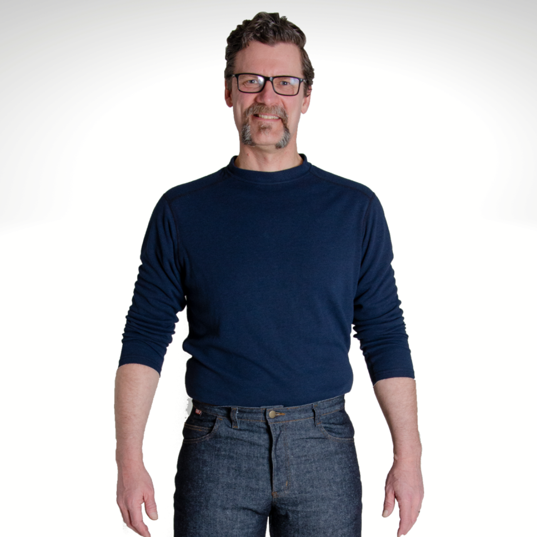 Image of MWG TRANSMISSION FR long-sleeve t-shirt in navy. MWG TRANSMISSION is a lightweight inherent FR fabric. Model is wearing MWG TRANSMISSION FR shirt tucked in to MWG FR blue jeans.