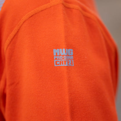 Image of MWG logo and CAT 2 rating on MWG EVOLUTION long-sleeve t-shirt. Logo is silver in colour on bright orange flame-resistant (FR) fabric. MWG EVOLUTION is a lightweight inherent FR fabric.