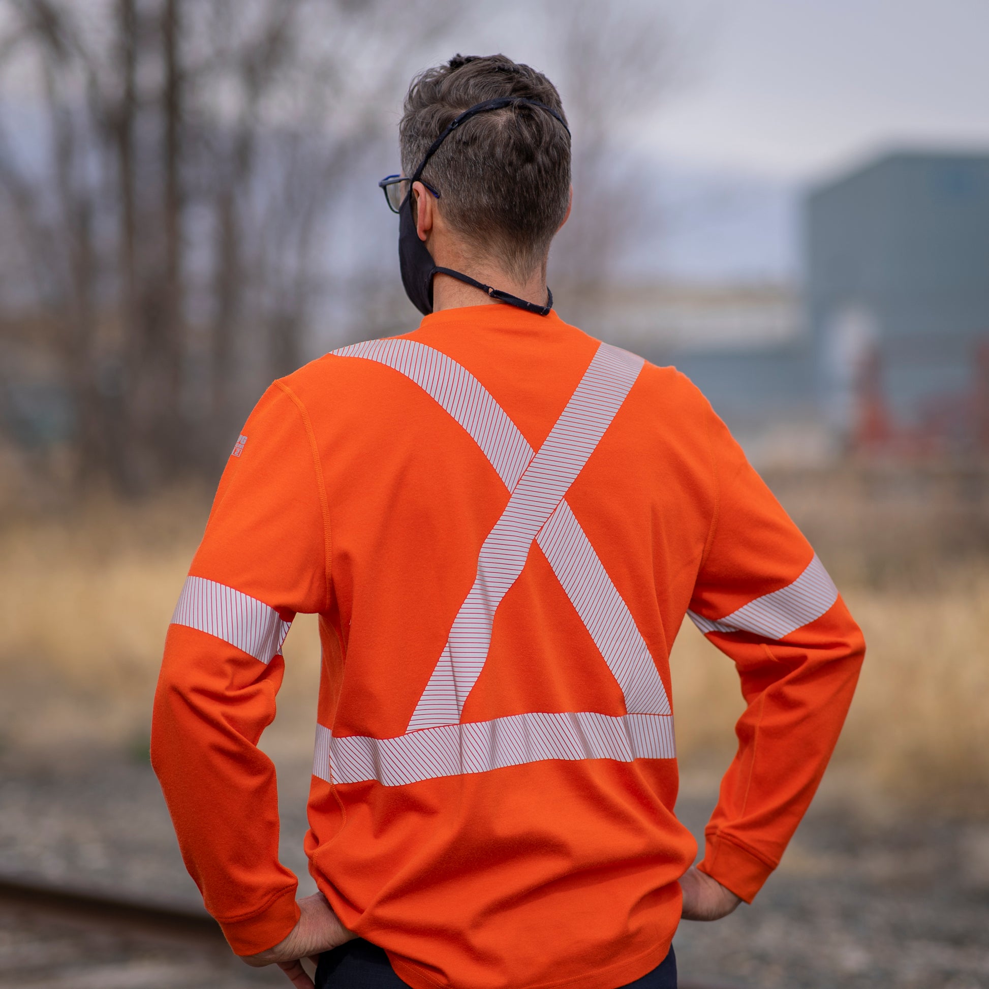 Back view of MWG EVOLUTION FR Long-Sleeve T-Shirt. MWG EVOLUTION Shirt is bright orange in colour with silver segmented reflective tape to meet CSA Z96-15 Hi-Vis standard. MWG EVOLUTION is a proprietary flame-resistant FR fabric blend that is lightweight with an 11 ATPV.