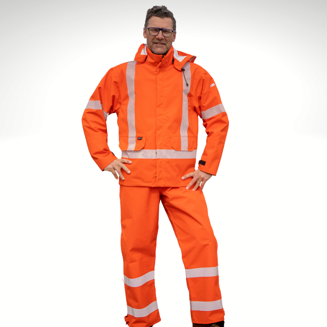 Image of MWG STORMSHIELD FR Rain Proof Bib. MWG STORMSHIELD FR Bib is bright orange in colour with silver segmented reflective tape on lower legs to meet high-visibility standard CSA Z96-15. Model is wearing MWG STORMSHIELD FR Bib with bright orange MWG STORMSHIELD FR rain jacket. MWG STORMSHIELD is a laminated inherent flame-resistant (FR) fabric.