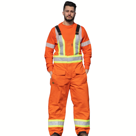 Image of Hi-Vis Cotton Duck Insulated Bib Pant. Bib pant is bright orange in colour with yellow/silver/yellow reflective tape on torso and legs to meet high-visibility standard CSA Z96-15. Bib straps are black in colour and two large front pockets with flaps are seen. Model is wearing bib pant over MWG TRANSMISSION long-sleeve shirt.