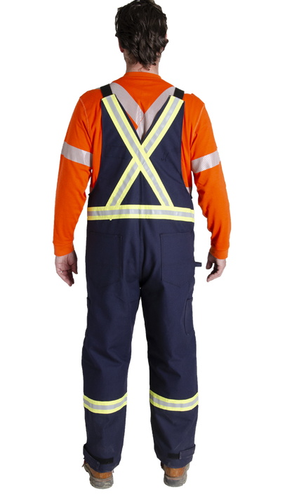 Back view of MWG Duck Canvas FRC Bib Overall. FR Overall is dark navy in colour with yellow/silver/yellow reflective tape in an X pattern on upper back to meet high-visibility standard CSA Z96-15. Reflective tape is also on each leg below the knee. Overalls are made with inherent flame-resistant (FR) canvas.