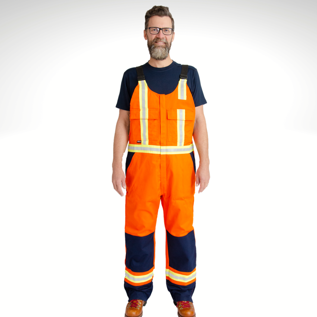 Image of MWG COTTON COMFORT FR Bib Overall. The FRC bib overall is bright orange and navy in colour, with yellow/silver/yellow reflective tape on torso and legs. Image shows two large front pockets on chest and two front slant pockets on hips. Overall is made with MWG COTTON COMFORT flame-resistant (FR) cotton.