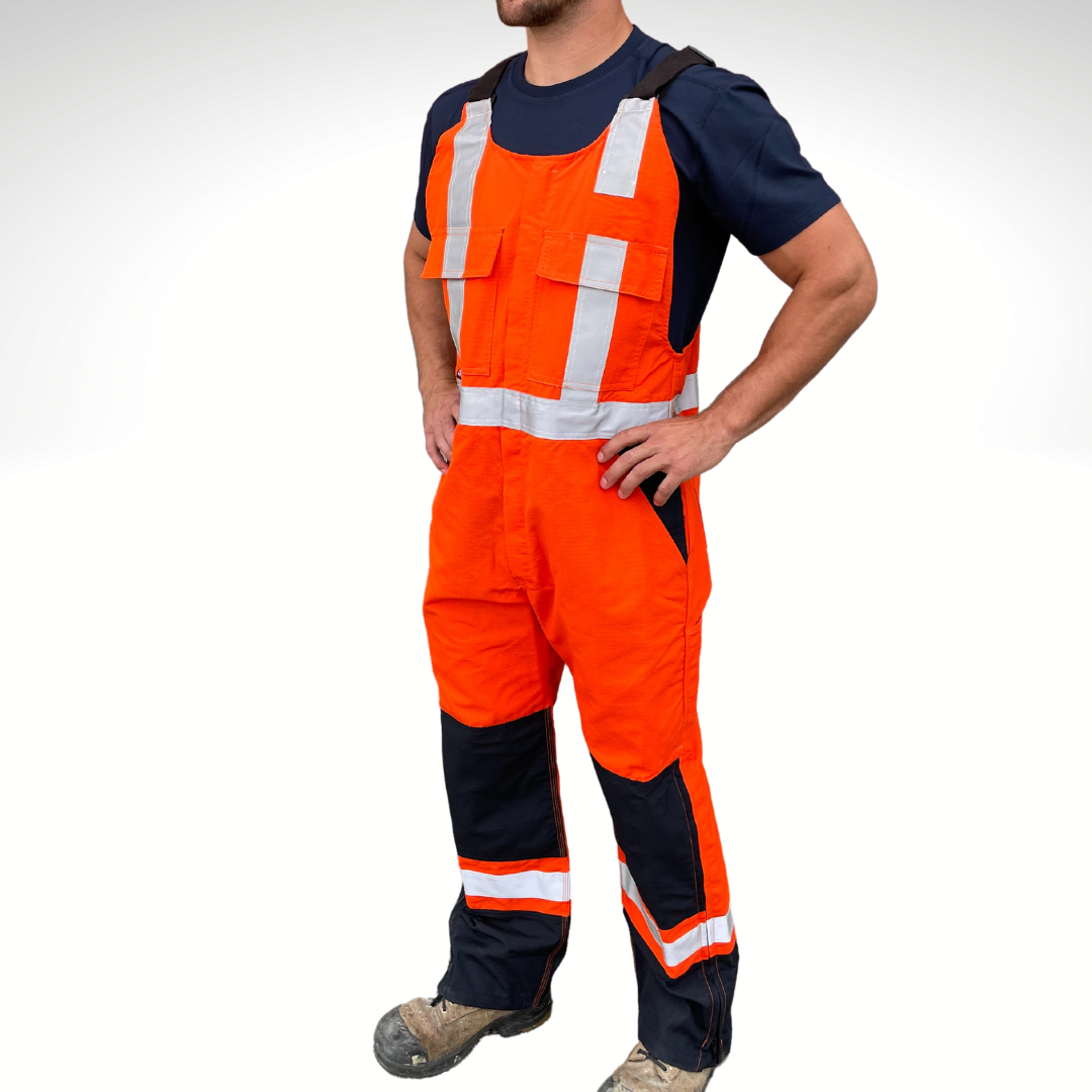 MWG RIPGUARD Men's FR Bib Overall. Men's FR Overall is bright orange and navy with silver reflective striping on torso and legs for high-visibility. FR Overalls have two chest pockets with flaps, two FR leg zippers, and a front FR zipper. FR Overalls have black FR adjustable shoulder straps. FR Overalls are made with MWG RIPGUARD, a flame-resistant ripstop fabric. FR Overalls have a CAT 2 FR rating.