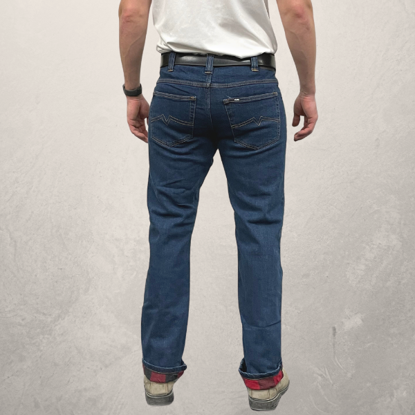 Back view of MWG Flannel-Lined Men's Stretch Denim Jean. Flannel-lined jeans are navy with gold stitching. Cuffs are rolled slightly to display red and black flannel lining. Jeans have two large back pockets.