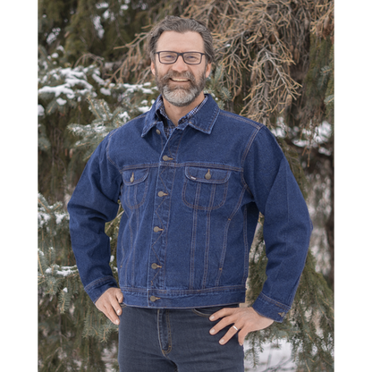 Image of MWG Storm Rider Men's Denim Jacket. MWG jean jacket is navy in colour with gold stitching and buttons. Denim jacket has two large chest pockets and slant pockets on lower torso. Model is wearing MWG Storm Rider Jacket with MWG stretch denim blue jeans.