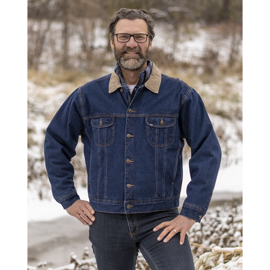 Image of MWG Storm Rider Lined Denim Jacket. MWG Storm Rider Jacket is dark navy in colour with gold stiching and a tan corduroy collar. Jacket has gold buttons and two large chest pockets. Model is wearing MWG Jean Jacket with MWG stretch denim blue jeans.