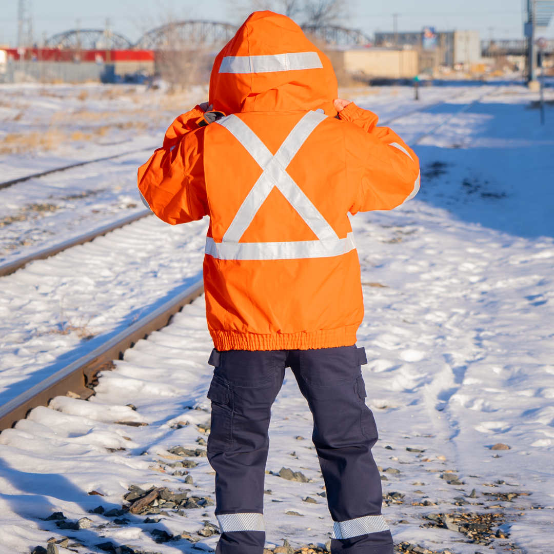 Back view of MWG STORMSHIELD FR/AR Winter Jacket. FR Jacket is bright orange with silver reflective tape in an X pattern on upper back for high-visibility. Hood has a silver reflective stripe from ear to ear. MWG STORMSHIELD is an inherent flame-resistant ripstop fabric. Men's FR Freezer Jacket is zipped in for additional warmth.