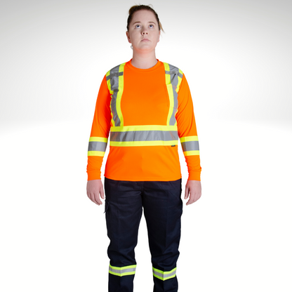 Image of MWG Women's Hi-Vis Long Sleeve T-Shirt. Women's Long Sleeve shirt is bright orange with yellow/silver/yellow reflective tape on torso and sleeves to meet high-visibility standard CSA Z96-15. Model is wearing Hi-Vis Shirt with navy Hi-Vis cargo pants.